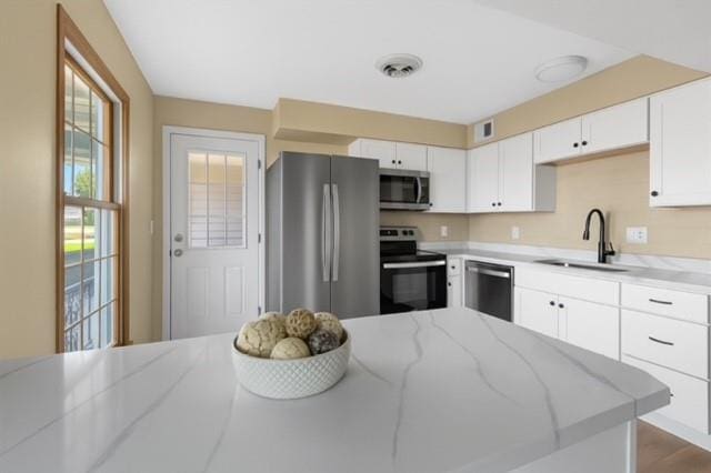 853 Dumont Pl Unit A, Saint Louis, MO 63125 - kitchen featuring appliances with stainless steel finishes, a sink, light stone countertops, white cabinets, and wood finished floors