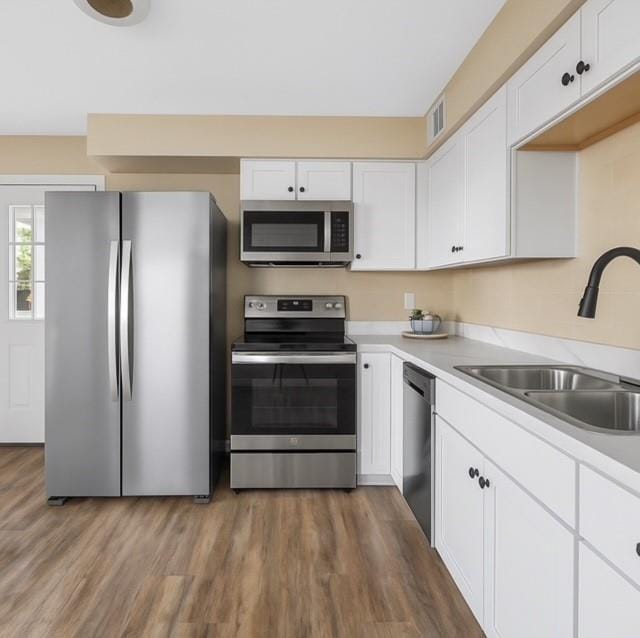 853 Dumont Pl Unit A, Saint Louis, MO 63125 - kitchen featuring appliances with stainless steel finishes, a sink, white cabinets, light countertops, and wood finished floors