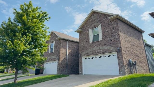 view of home's exterior with a garage, driveway, and brick siding