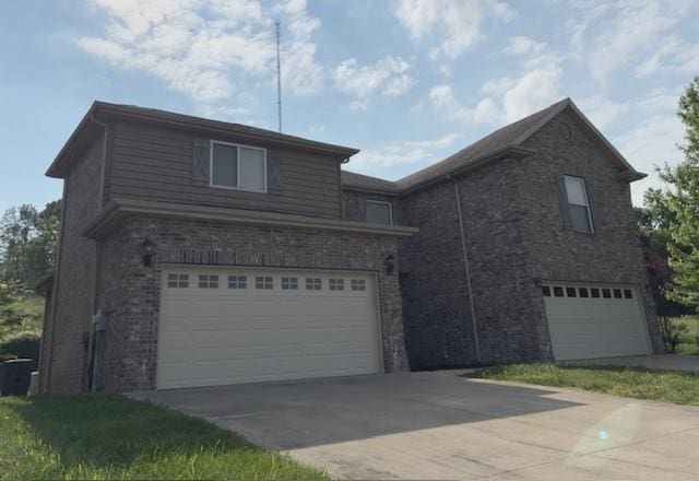 traditional-style home featuring an attached garage, concrete driveway, and brick siding