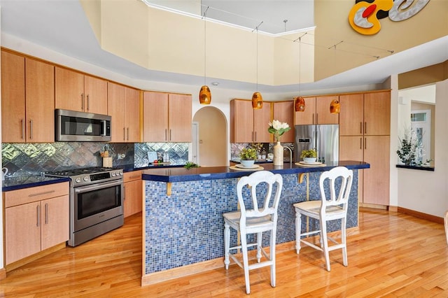 169 Fick Farm Rd, Chesterfield, MO 63005 - kitchen with stainless steel appliances, dark countertops, a kitchen bar, and light wood-style flooring