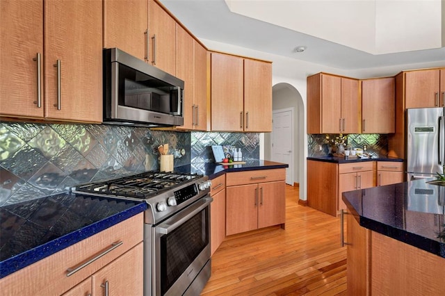 169 Fick Farm Rd, Chesterfield, MO 63005 - kitchen with stainless steel appliances, arched walkways, light wood finished floors, and tasteful backsplash