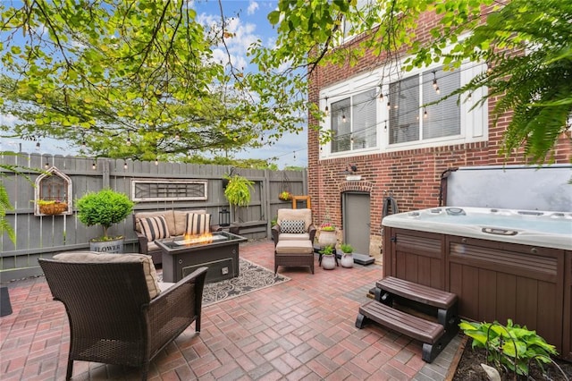 view of patio with a hot tub, a fire pit, and fence