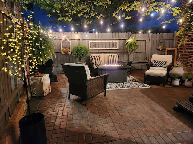 patio at night featuring an outdoor hangout area and a fenced backyard