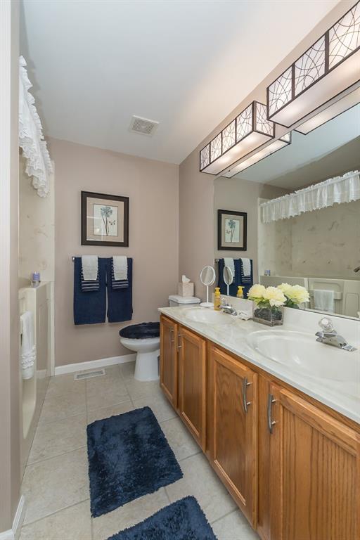 55 Rue De Paix Dr, Lake St Louis, MO 63367 - bathroom with double vanity, tile patterned floors, toilet, a shower with curtain, and baseboards