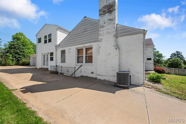 8261 Watson Rd, Saint Louis, MO 63119 - back of property featuring brick siding, a chimney, a patio area, and a garage