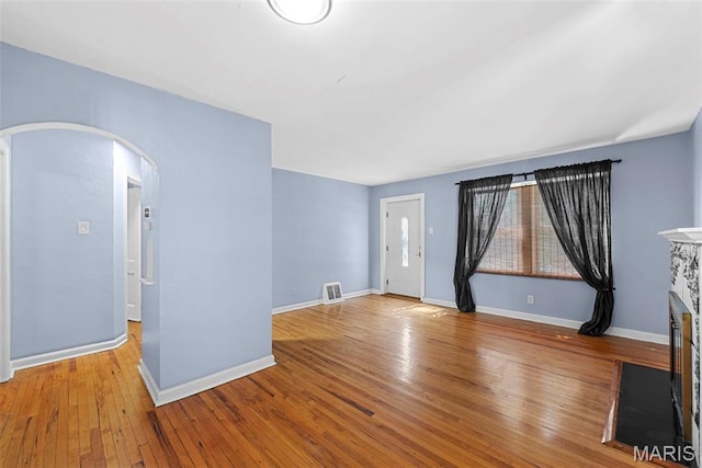 8261 Watson Rd, Saint Louis, MO 63119 - empty room with arched walkways, hardwood / wood-style floors, and a fireplace with flush hearth