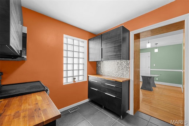 8261 Watson Rd, Saint Louis, MO 63119 - kitchen featuring butcher block counters, dark tile patterned floors, and backsplash