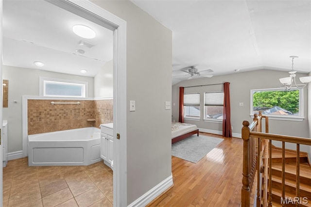 8261 Watson Rd, Saint Louis, MO 63119 - bathroom featuring a bath, lofted ceiling, plenty of natural light, a chandelier, and a ceiling fan