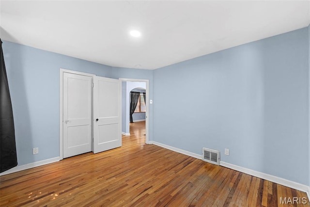 8261 Watson Rd, Saint Louis, MO 63119 - unfurnished bedroom with wood-type flooring, arched walkways, and recessed lighting