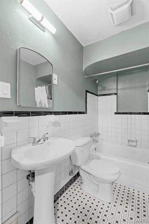 8261 Watson Rd, Saint Louis, MO 63119 - bathroom featuring tile patterned floors, tile walls, shower / bath combination with curtain, and wainscoting
