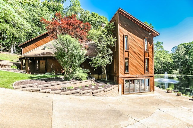 view of outdoor structure featuring a water view and concrete driveway