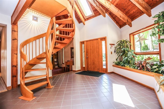 foyer with stairs, beamed ceiling, a skylight, high vaulted ceiling, and baseboards