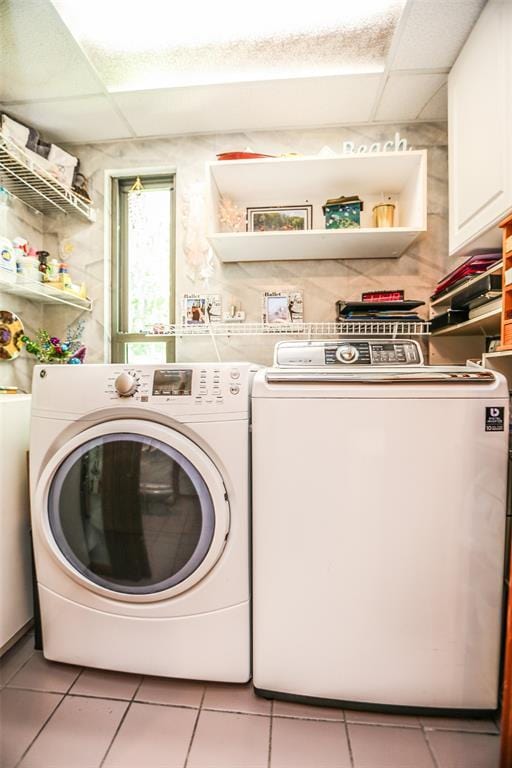 clothes washing area featuring cabinet space, washing machine and clothes dryer, and tile patterned floors
