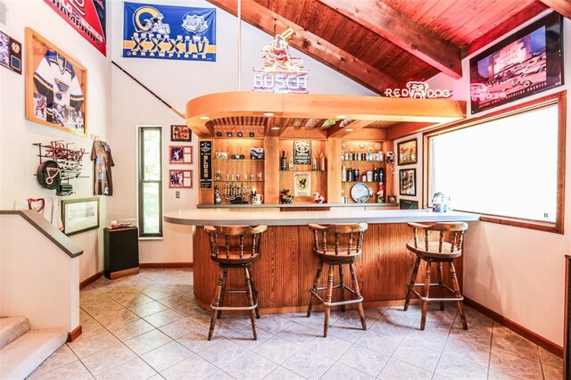 indoor dry bar featuring tile patterned floors, wood ceiling, stairway, and baseboards