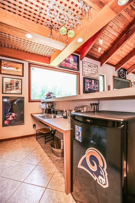kitchen with refrigerator, wooden ceiling, light tile patterned flooring, and baseboards