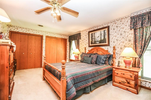 bedroom featuring wallpapered walls, carpet floors, multiple closets, and a ceiling fan