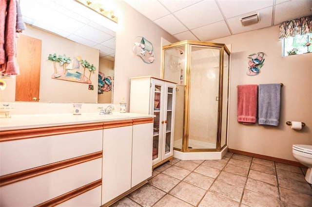 bathroom with a paneled ceiling, toilet, a stall shower, vanity, and tile patterned flooring