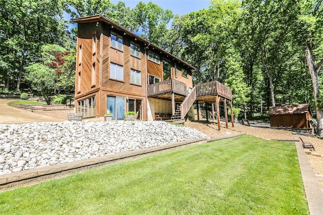 back of property with a deck, a lawn, stairs, a storage unit, and an outbuilding