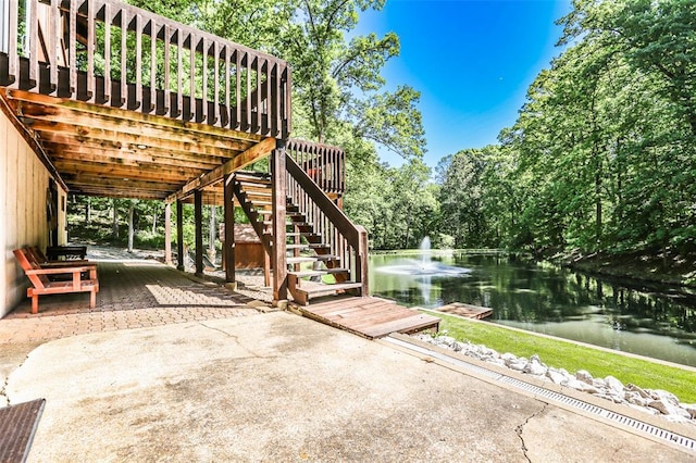 view of patio featuring stairway and a deck with water view