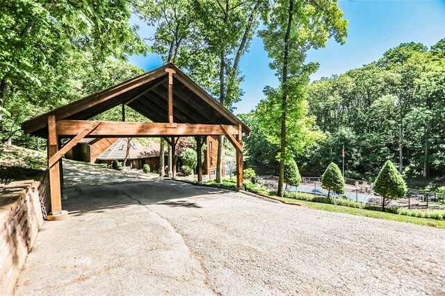 view of car parking featuring driveway, a carport, and fence