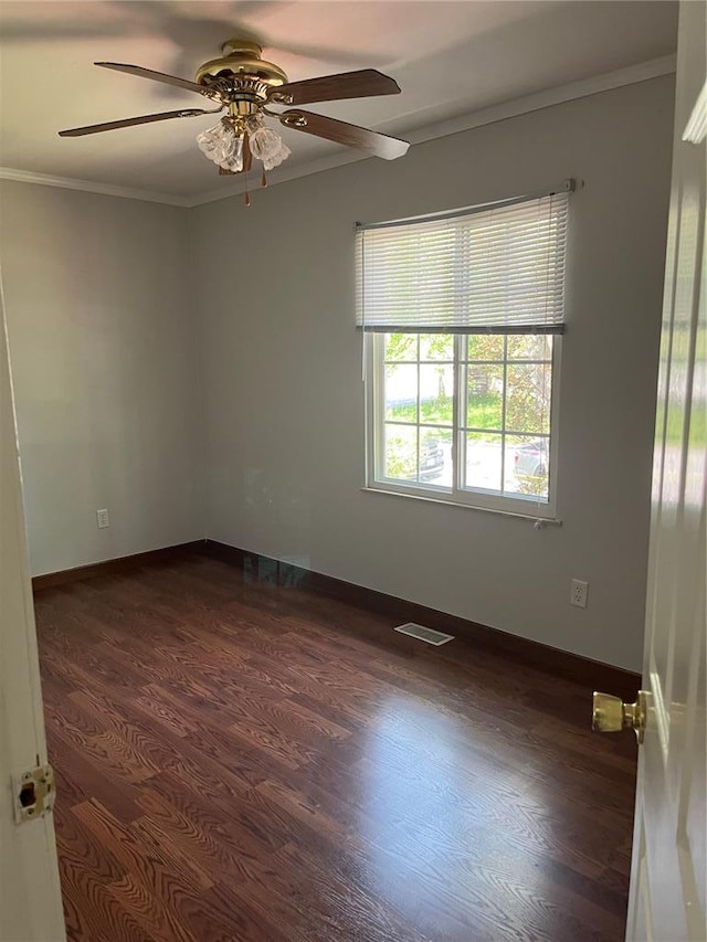 unfurnished room featuring crown molding, ceiling fan, dark wood-type flooring, and baseboards