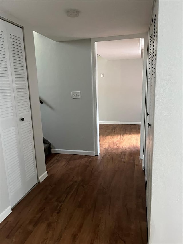 corridor with wood finished floors, baseboards, and stairway