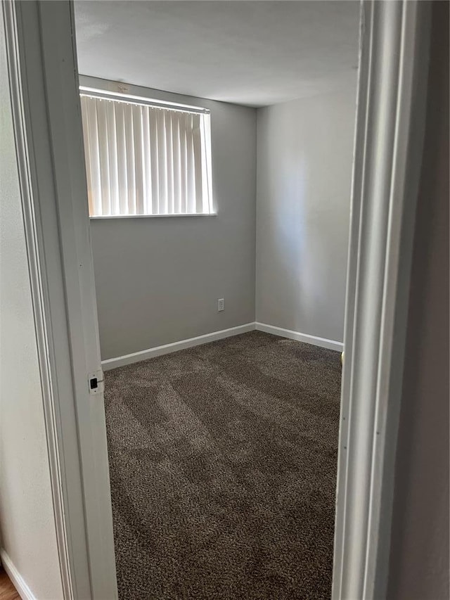 carpeted spare room featuring baseboards