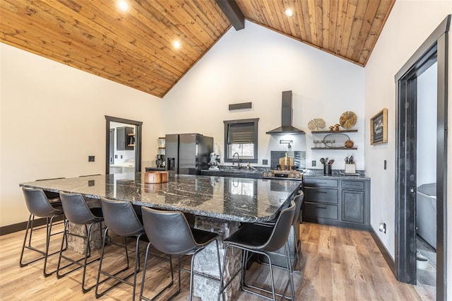 1300 River Valley Rd, Doniphan, MO 63935 - kitchen with black fridge, wall chimney range hood, high vaulted ceiling, a breakfast bar area, and light wood-style floors