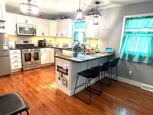 106 W Iowa St, Trenton, IL 62293 - kitchen featuring appliances with stainless steel finishes, wood finished floors, a peninsula, dark countertops, and a sink
