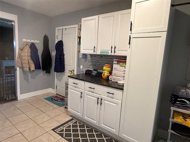106 W Iowa St, Trenton, IL 62293 - kitchen with dark countertops, white cabinetry, backsplash, light tile patterned flooring, and baseboards