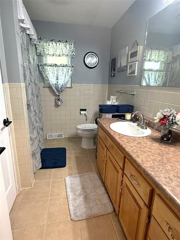 106 W Iowa St, Trenton, IL 62293 - bathroom featuring tile walls, tile patterned flooring, vanity, toilet, and wainscoting