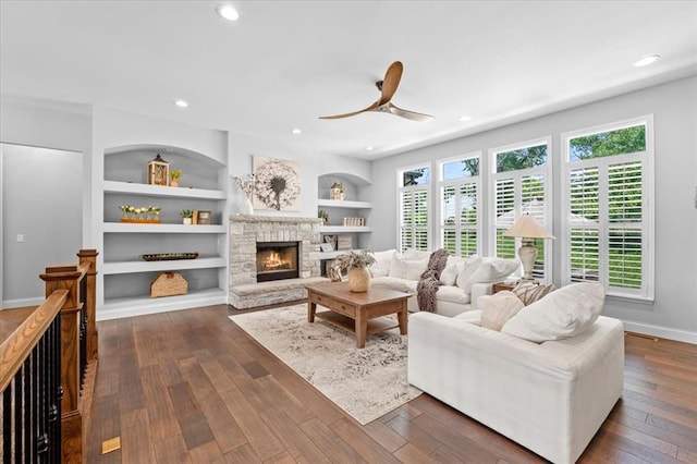 2604 Center Ave, Wildwood, MO 63040 - living room featuring a ceiling fan, dark wood-style floors, a stone fireplace, built in features, and recessed lighting