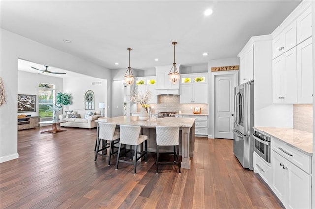 2604 Center Ave, Wildwood, MO 63040 - kitchen featuring stainless steel appliances, a breakfast bar area, tasteful backsplash, open floor plan, and white cabinetry