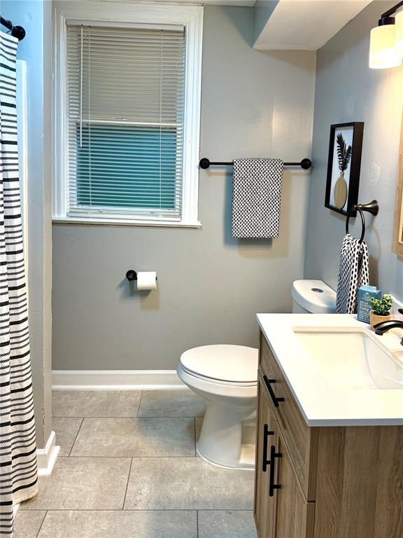 2327 Shirley Ave, Jennings, MO 63136 - full bathroom with vanity, toilet, tile patterned flooring, and baseboards