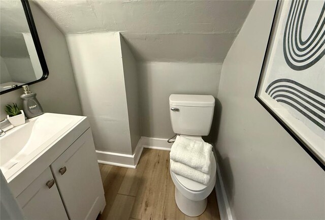 2327 Shirley Ave, Jennings, MO 63136 - bathroom with toilet, wood finished floors, baseboards, vanity, and vaulted ceiling