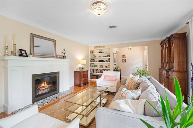 5 Homestead Acres, Olivette, MO 63132 - living area featuring a glass covered fireplace, wood finished floors, built in shelves, and baseboards