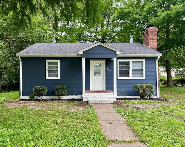 317 Marion Ave, Sikeston, MO 63801 - view of front of house with a chimney, a front lawn, and roof with shingles