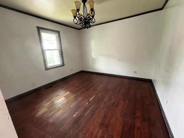 spare room with dark wood-style flooring, a chandelier, baseboards, and ornamental molding