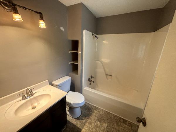 full bathroom featuring toilet, vanity, and tub / shower combination