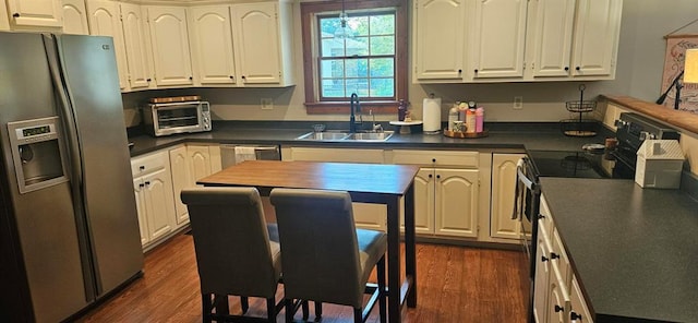 kitchen with stainless steel appliances, a sink, dark countertops, and dark wood finished floors