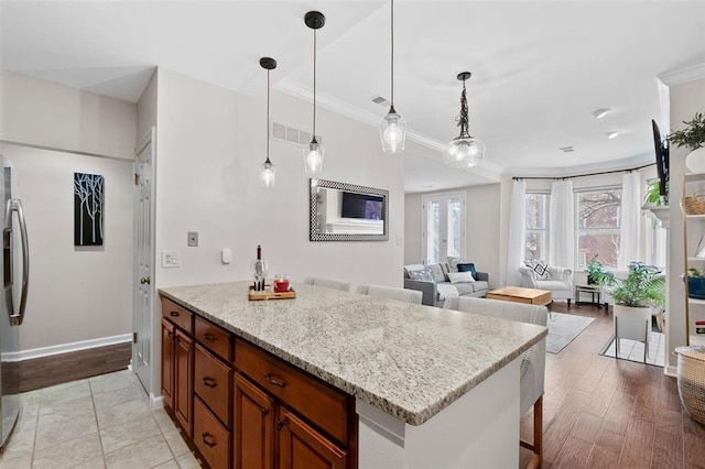 230 N Boyle Ave Unit B, Saint Louis, MO 63108 - kitchen featuring crown molding, brown cabinetry, decorative light fixtures, baseboards, and light stone countertops