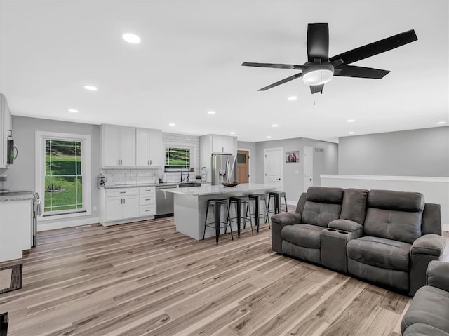 living room with light wood-type flooring, recessed lighting, healthy amount of natural light, and ceiling fan