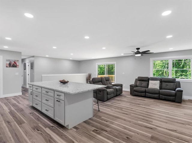 living area featuring wood finished floors, recessed lighting, baseboards, and a ceiling fan
