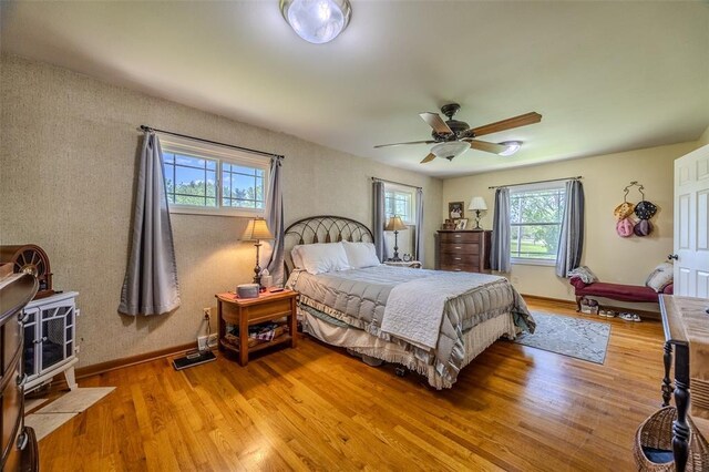 310 Smith Rd, Lebanon, MO 65536 - bedroom with light wood finished floors, ceiling fan, baseboards, and a wood stove