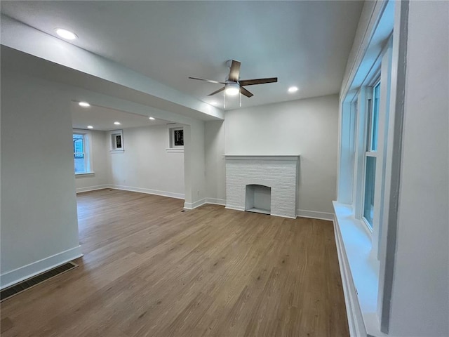 unfurnished living room with wood finished floors, recessed lighting, baseboards, a fireplace, and ceiling fan