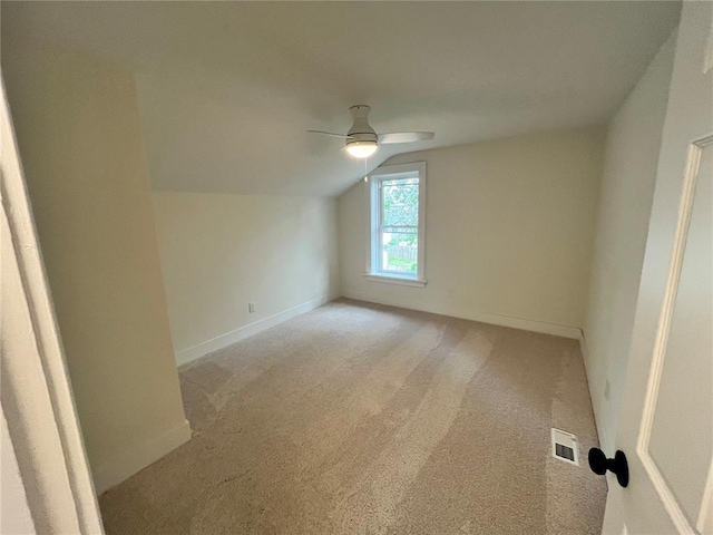 additional living space with ceiling fan, vaulted ceiling, light carpet, and baseboards