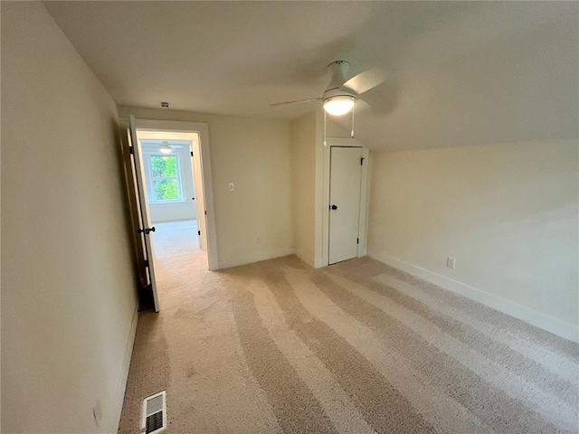 spare room featuring light carpet, ceiling fan, and baseboards