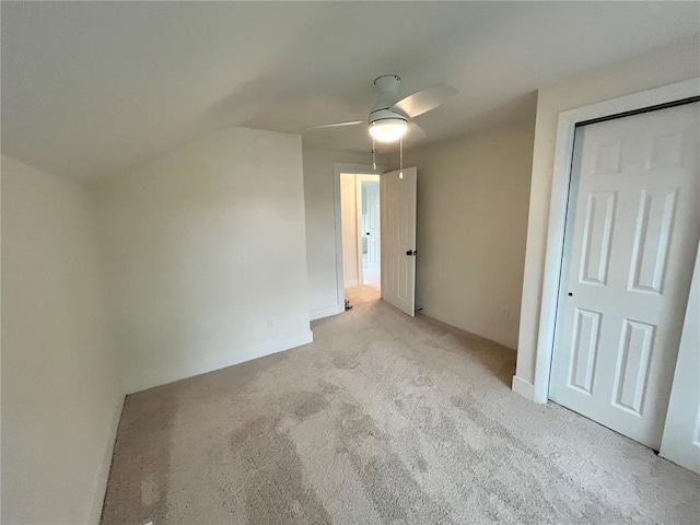 unfurnished bedroom with light colored carpet, ceiling fan, and vaulted ceiling