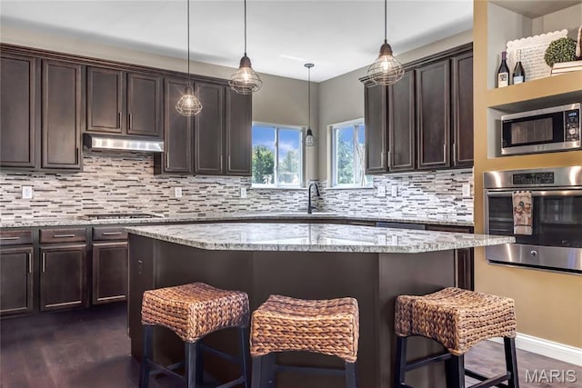 2001 Paul Renaud Blvd, Lake St Louis, MO 63367 - kitchen with appliances with stainless steel finishes, a breakfast bar area, dark brown cabinetry, and decorative backsplash